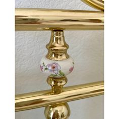 a close up of a gold metal bed frame with flowers painted on the bottom and sides