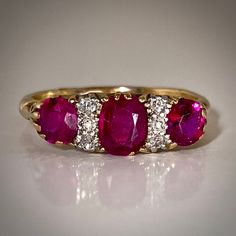 This is a beautiful antique English ruby and diamond ring from the late 19th century. Featuring three old cut rubies that graduate in size and are set in gold prongs. The central ruby's calculated weight is 0.64ct, based on estimated dimensions of 5.8 by 4.2 by 2.4mms (approx. TCW 1.1 ct). MEASURES: 7 ½ (US) - can be resized within reason by your skilled jeweler. Vintage Three Stone Ruby Ring For Formal Occasions, Classic Three Stone Ruby Ring, Heirloom Three Stone Ruby And Diamond Ring, Antique Three Stone Ruby Ring For Formal Occasions, Vintage Three Stone Ruby Ring For Anniversary, Heirloom Ruby Diamond Ring, Heirloom Ruby Ring With Three Stones In Round Cut, Heirloom Three Stone Ruby Ring With Diamonds, Vintage Three Stone Ruby Ring For Wedding