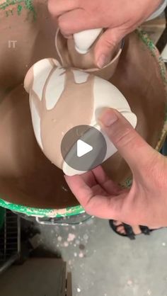 a person is making something out of clay in a bowl with their hands and fingers