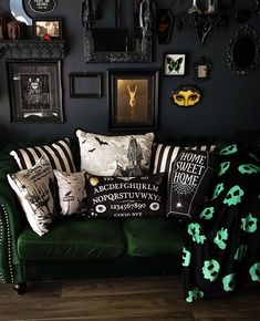 a green couch with black and white pillows on top of it next to framed pictures