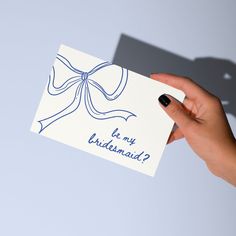 a hand holding a card with a bow on it that says is my bridesmaid?