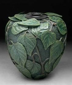 a green vase with leaves on it