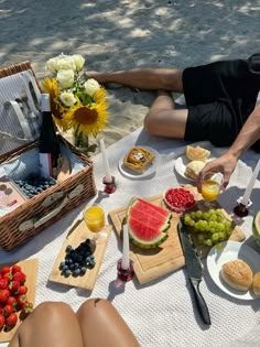 a man laying on the ground with food and drinks in front of him, including watermelon