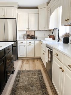 a kitchen with white cabinets, black appliances and an area rug in the middle of the floor