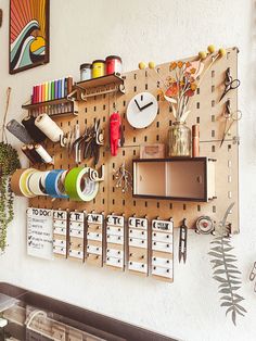 a peg board with many items on it and some plants in the corner next to it