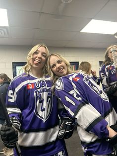 two women in hockey uniforms standing next to each other with their arms around each other