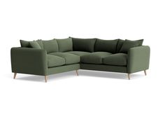 a green sectional sofa with pillows on the back and arms, sitting in front of a white background