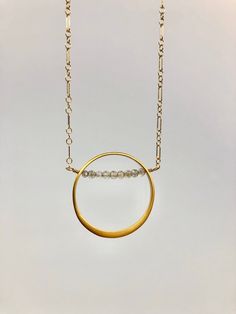 "This unique vermeil gold circle features a tiny row of faceted labradorite gems nestled among the pendant. The pendant is housed on a 14 karat elongated link chain that is delicate and strong. Please choose between 16\" and 18\" lengths. 14 karat gold fill lobster clasp. Vermeil is 24 karat gold over sterling silver. This pendant has a lovely matte finish."