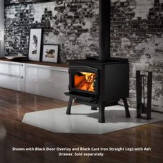 a black stove sitting on top of a hard wood floor next to a brick wall