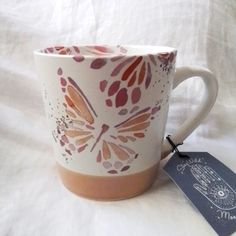 a coffee cup with a butterfly design on it and a tag attached to the side