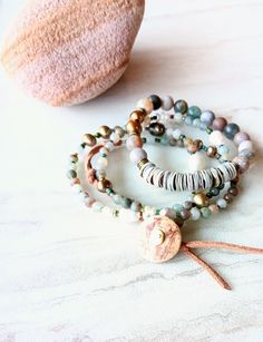 "First, at almost 22\" in length, this beaded strand can be worn as a necklace and a triple wrap bracelet if you like. Muted greens, grays, beige, gold, desert rose, touches of orange, rust, army green, beige, and more. A great mix of washed out color like a beaten ocean landscape. 6mm to 11mm Pearl, matte 4mm Moss Agate, matte Sunstone, matte 4mm  Jasper stones, and accents of seed beads, and metals. Distressed natural suede loops and coconut button closure make extendable. One-of-a-kind. The i