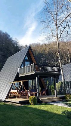 a large house with a metal roof in the middle of a grassy area next to trees