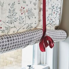 the curtain is tied to the window with a red ribbon around it and hanging in front of a window sill