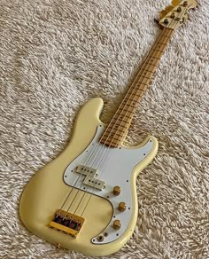 a yellow electric guitar laying on top of a white carpet covered in furnishing