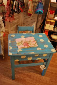 a blue table with white polka dots on it in a room filled with clothes and other items