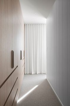 an empty hallway leading to a bedroom with white curtains