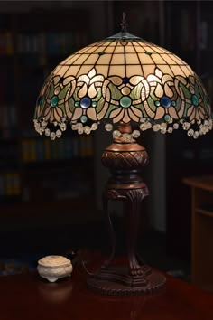 a stained glass lamp sitting on top of a wooden table next to a book shelf