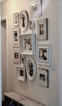 a white wall with many pictures on it and a bench in front of the wall