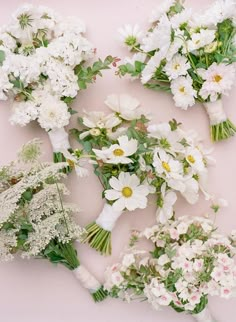 several bouquets of white flowers laid out on a pink surface