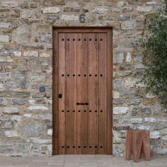 a wooden door sitting next to a stone wall with a tree in front of it