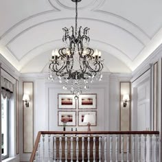 a chandelier hanging from the ceiling in a room with white walls and wood floors