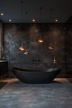 a large black bath tub sitting under three lights