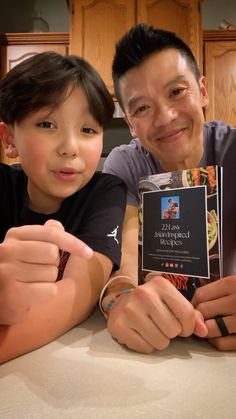 a man and boy posing for a photo with an award in front of them on a kitchen counter