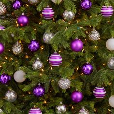 the christmas tree is decorated with purple and silver ornaments