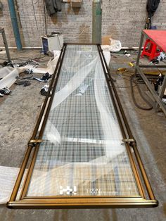 a glass table with metal frame and mesh covering on the top, sitting in a warehouse