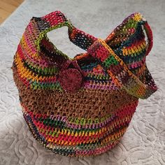 a multicolored purse sitting on top of a bed