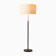 a floor lamp with a white shade on top and a black base, against a white background