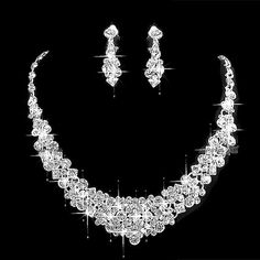 a diamond necklace and earring set on a black background