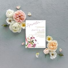 the wedding stationery is laid out on top of the table with pink and white flowers