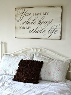 a bed with pillows and a sign above it that says you have my heart for my side up