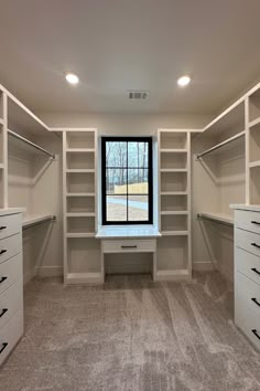 an empty walk in closet with shelves and drawers on either side of the window sill