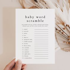 a person holding up a baby word scramble book with feathers on the table next to it