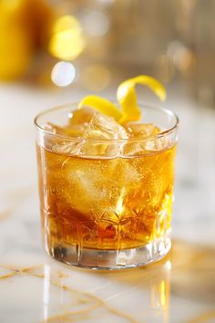 a glass filled with ice and lemons sitting on top of a marble countertop