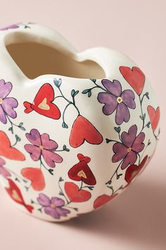 a white vase with red, purple and pink flowers painted on it's sides