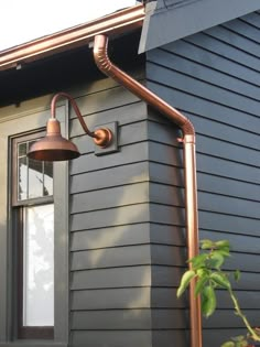 an outdoor light on the side of a house next to a potted plant and window