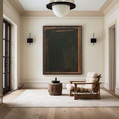 an empty living room with a painting hanging on the wall and two chairs in front of it