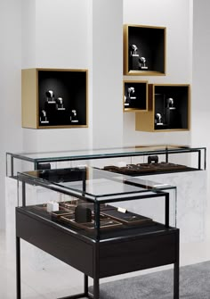 a glass table with some pictures on the wall behind it in a room that is white and black