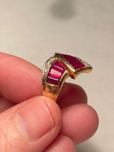 "Stunning art deco 14K synthetic Ruby and natural earth-mined Diamond Bypass wide band Ring. the ring is a size 6.5 and weighs 5 grams. The face measures 5/8\" tall at the widest measurement. Nine 5mm x 3mm tapered baguette rubies in open back channel setting with eight pave set round cut diamonds. Marked 14K, GA. Excellent condition. The stones are an intense red to fuchsia." Art Deco Gold Ruby Ring, Heart Piercing, Dagger Earrings, Diamond Baguette, Wide Band Ring, Channel Setting, Vintage Studio, Wide Band Rings, Star Art