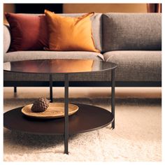 a living room with a couch, coffee table and pillows on the floor in front of it