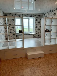 an empty room with shelves and drawers in front of a large window that has birds on it