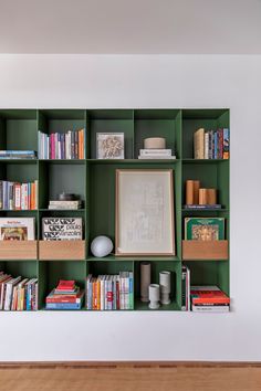 a bookshelf filled with lots of books next to a wall mounted art piece