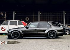 two cars parked next to each other in front of a fence