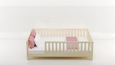 a doll's crib with a pink pillow and white sheets on the bed