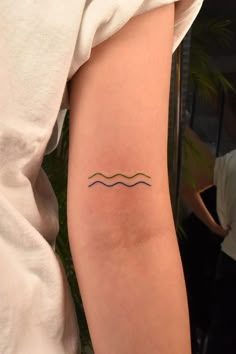 a woman's arm with a tattoo on it that has waves in the water