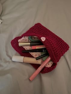 the contents of a purse are neatly arranged on a white bed with a red knitted blanket