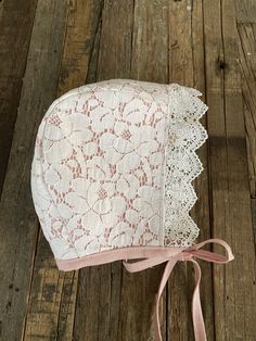 a pink and white lace bonnet on a wooden floor